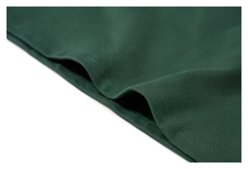 Close-up of a dark green garment hem with double-stitched seams.