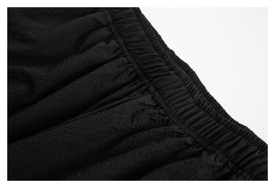 Detailed view of the black shorts' gathered elastic waistband and stitching.