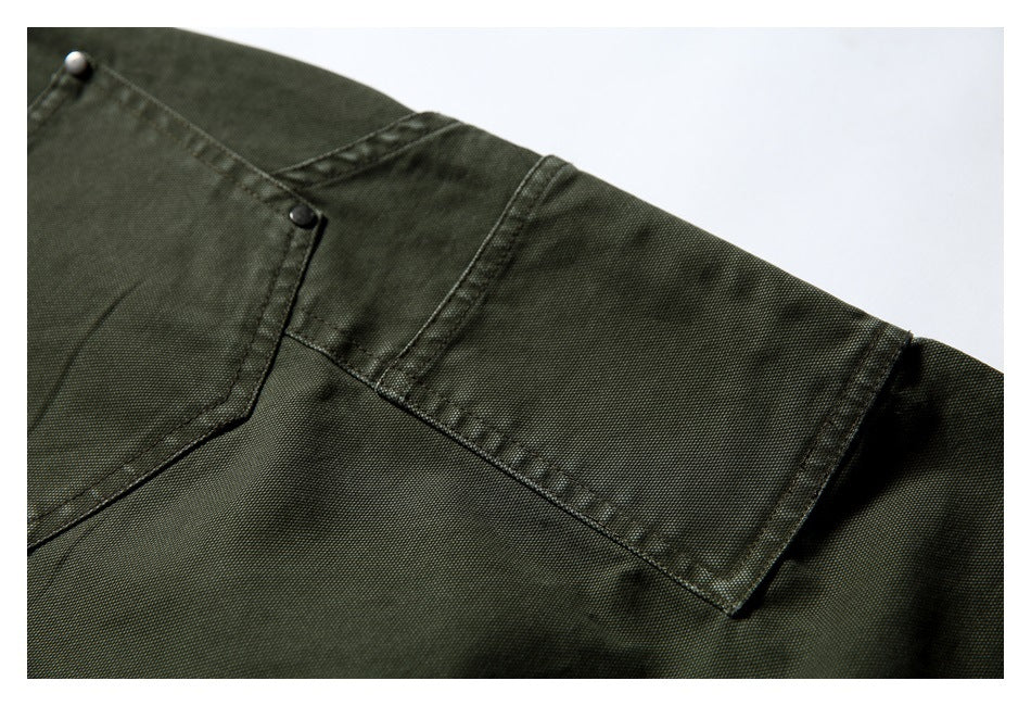Close-up of olive trousers showing a patch pocket edge and reinforced stitching.