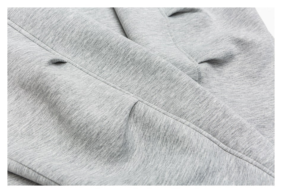 Close-up of a stitched seam and small opening on heather-gray fabric.
