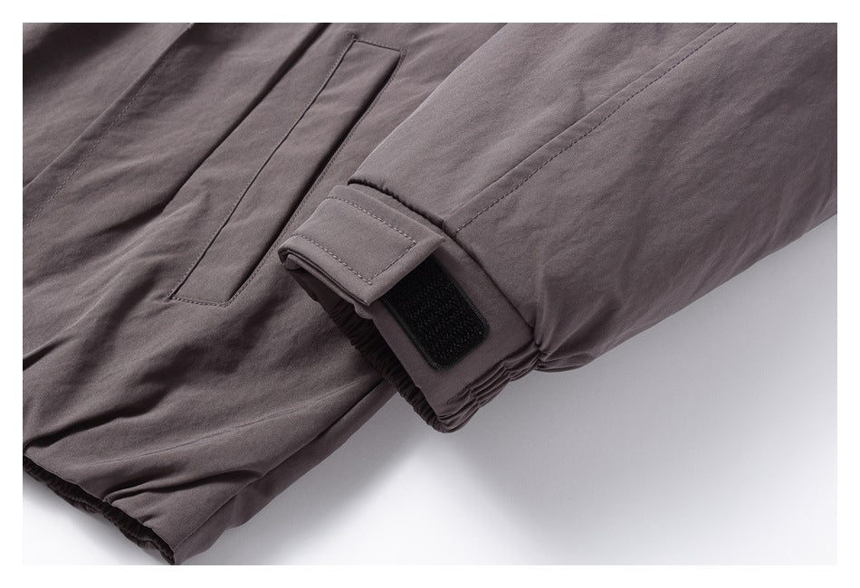 Close-up showing a dark gray jacket's sleeve cuff tab and slanted pocket.