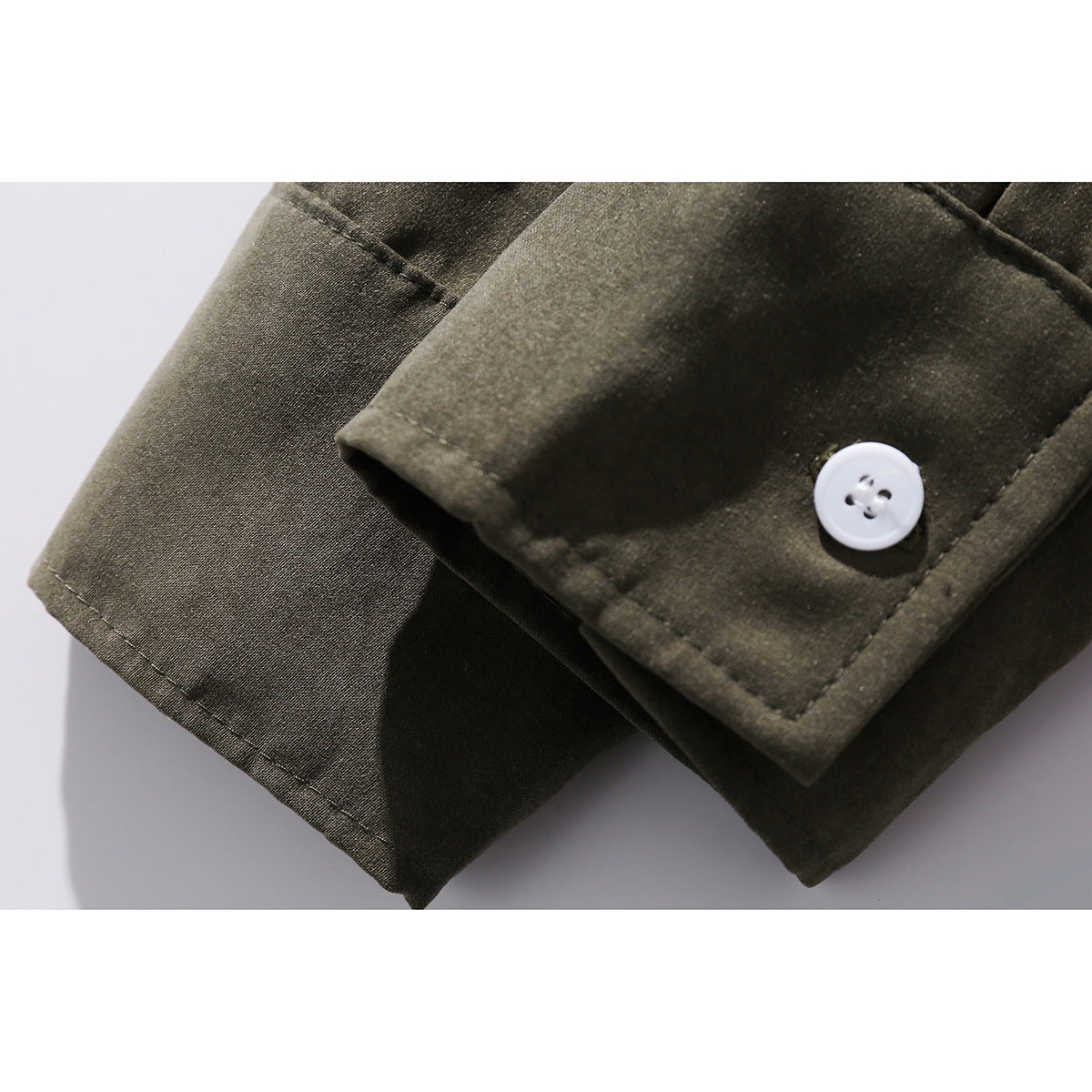 Close-up of an olive shirt cuff with a white button and visible stitching.