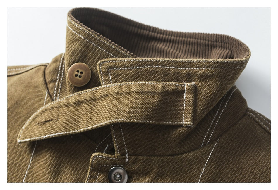 Close-up of a brown workwear jacket collar with a button, snap, and contrasting double stitching.