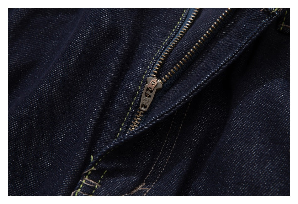 Close-up of a metal zipper and contrast stitching on dark indigo jeans.
