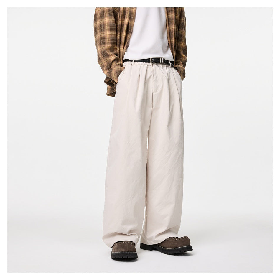 Front view of a model wearing ivory wide-leg trousers with a brown plaid shirt and dark shoes.