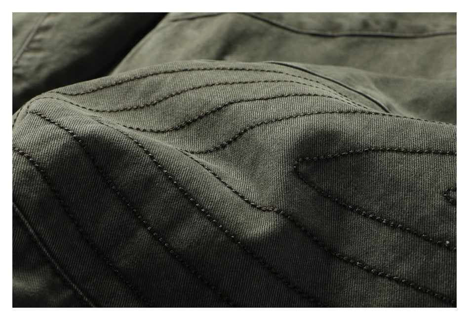 Close-up of layered curved stitching on dark olive-gray pants.