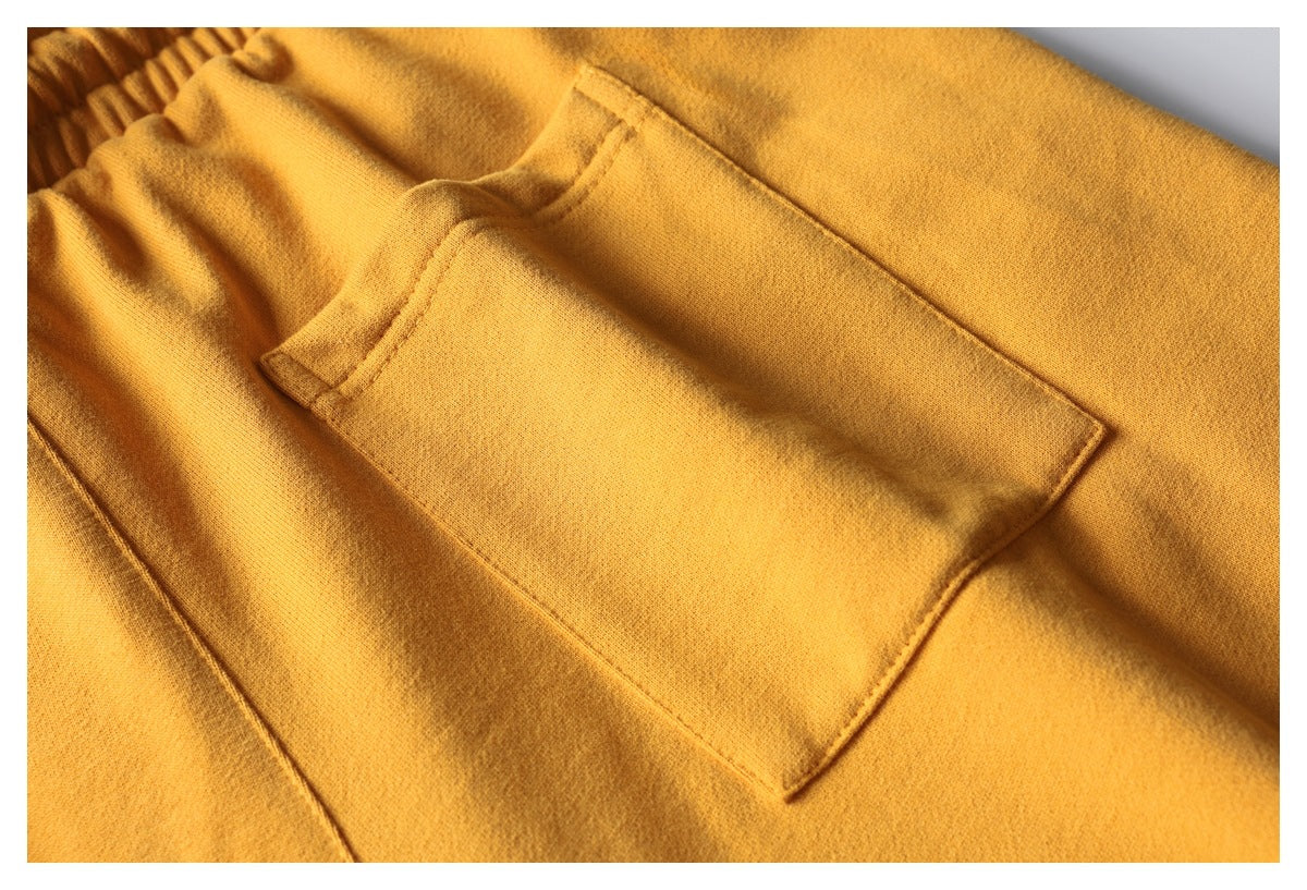 Close-up of a mustard-yellow garment showing a stitched rectangular patch pocket.