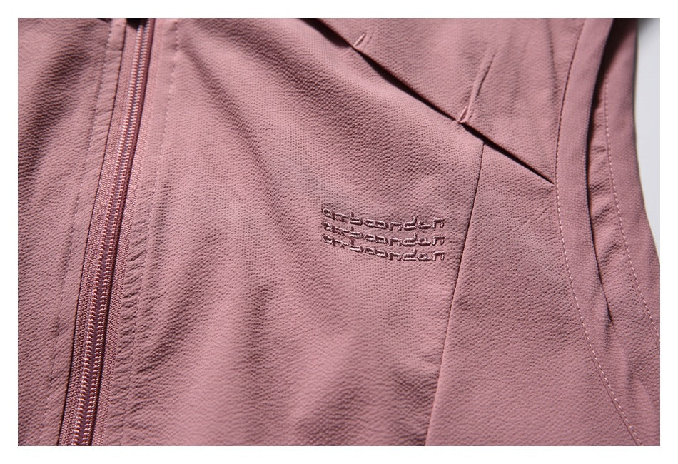 Close-up of the dusty rose vest's embroidered chest mark, zipper and angled seam.