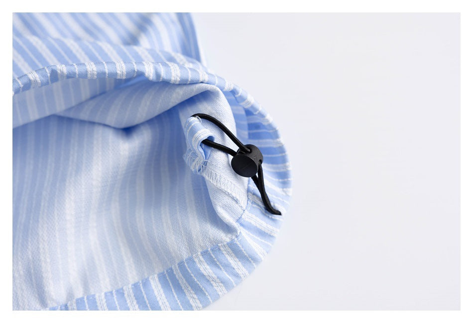 Close-up of a black cord lock on the edge of light blue, white-striped shorts.