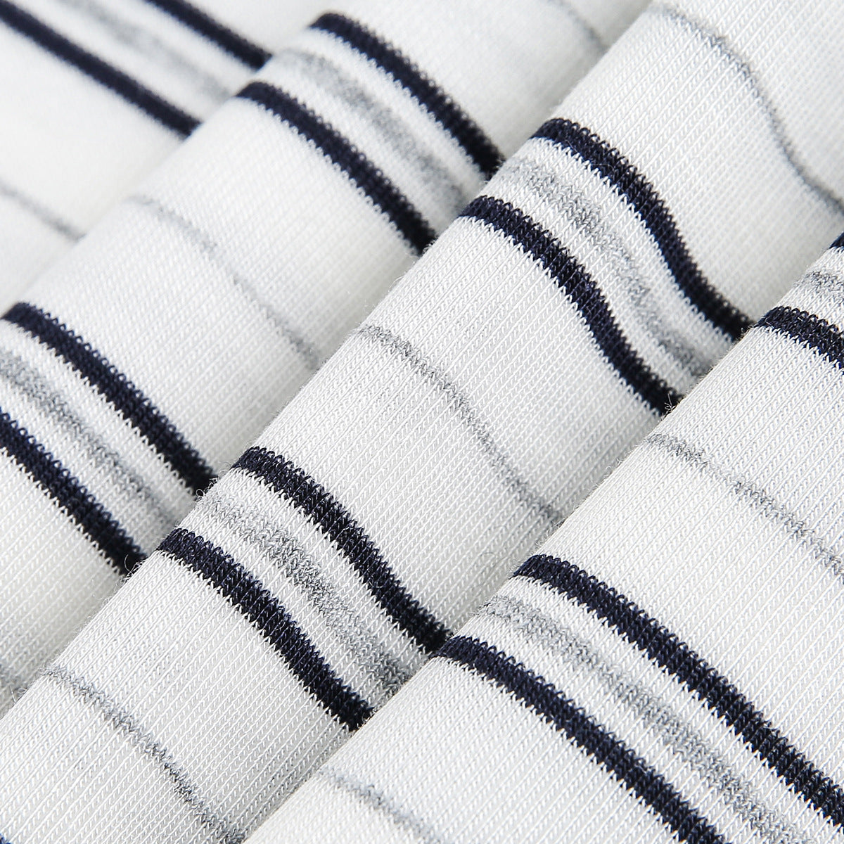 Extreme close-up of white ribbed knit fabric with narrow dark stripes.