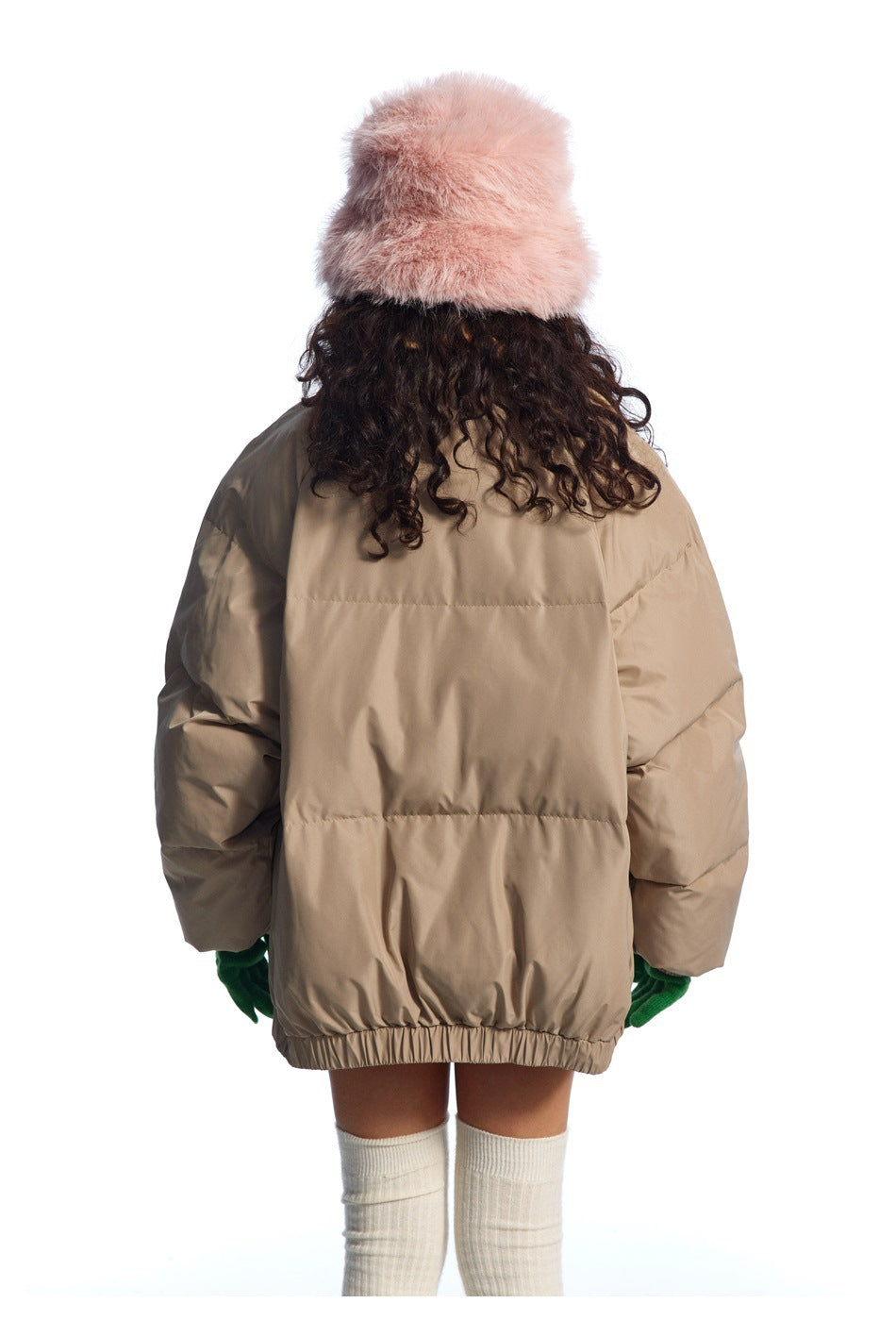 Back view of a beige oversized puffer jacket worn with a pink fur hat and cream knee-high socks.