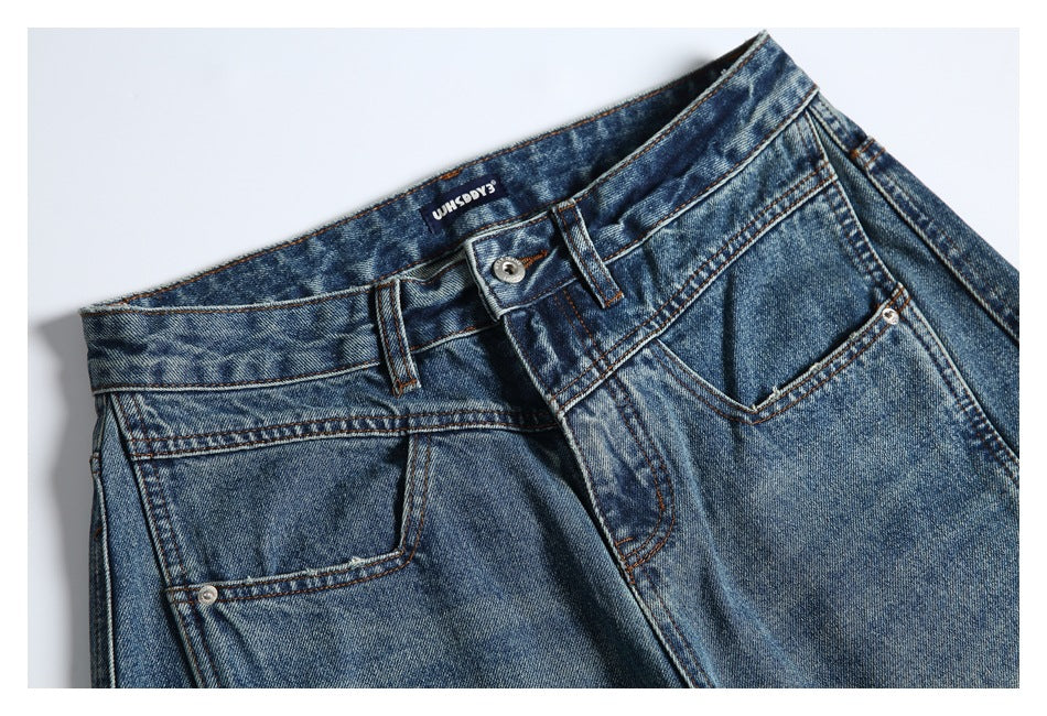 Close-up front view of blue-wash jeans showing the waistband, button, zipper fly, and front pockets.