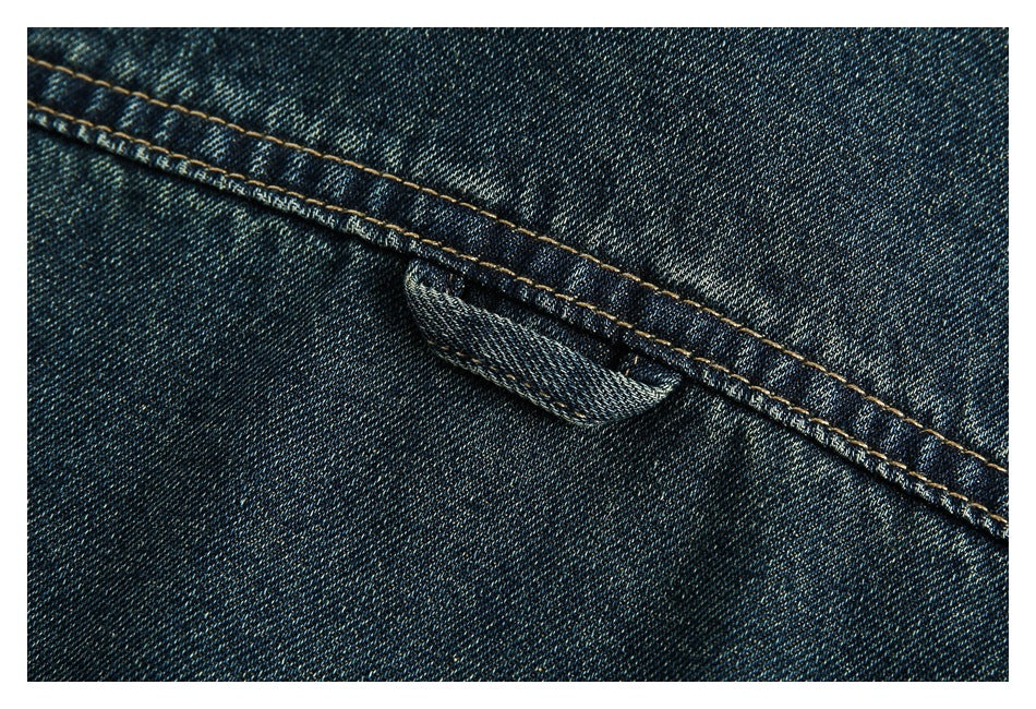 Close-up of a stitched seam and small denim loop on dark indigo denim.