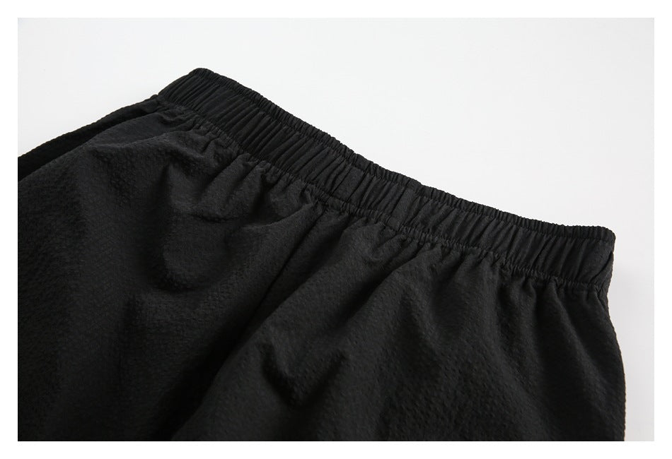 Close-up of black pants showing the gathered elastic waistband and textured fabric.