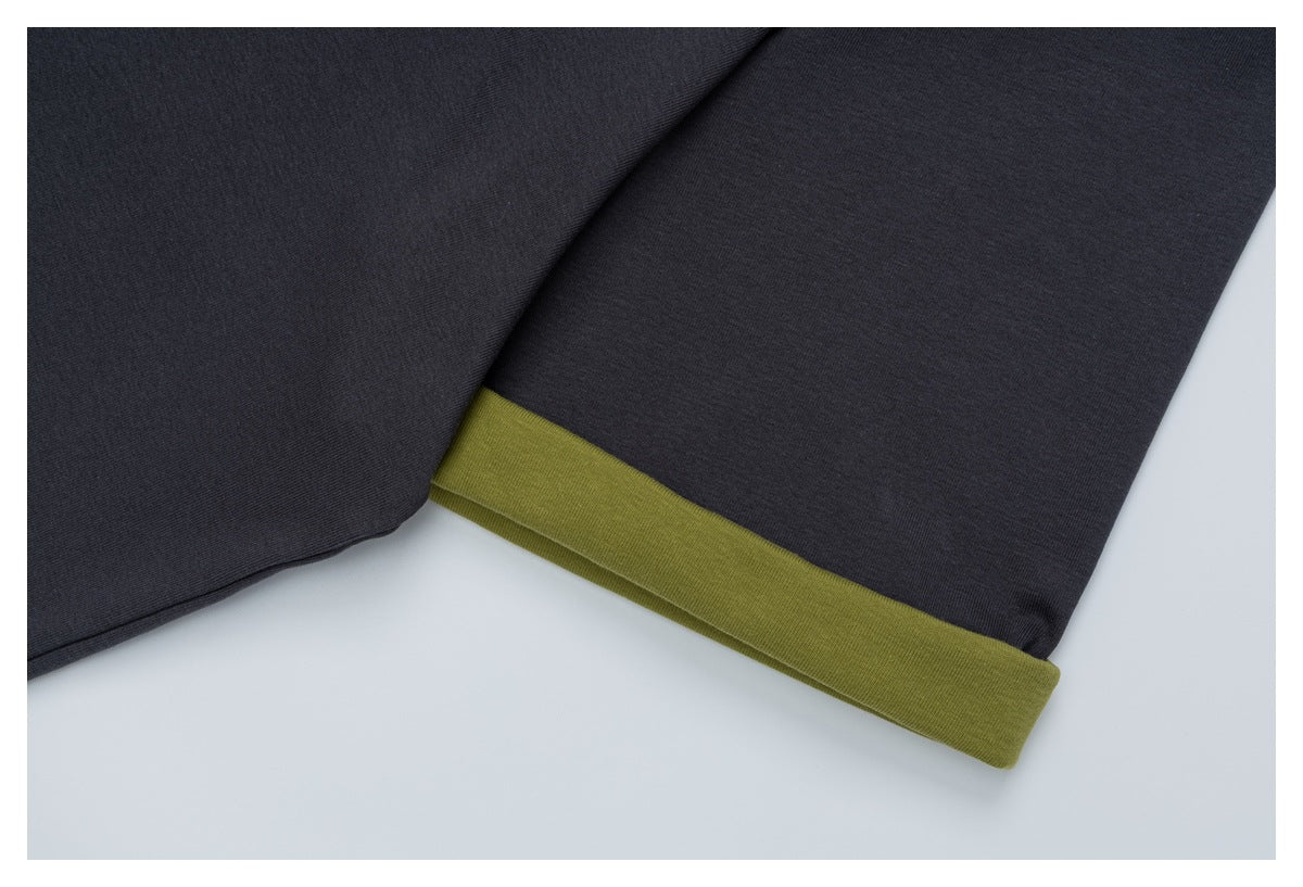 Close-up of a charcoal garment sleeve with an olive-green folded cuff.