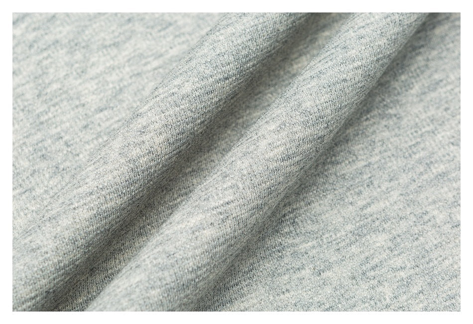 Close-up of light gray heathered fabric draped in soft folds, showing its fine knit texture.