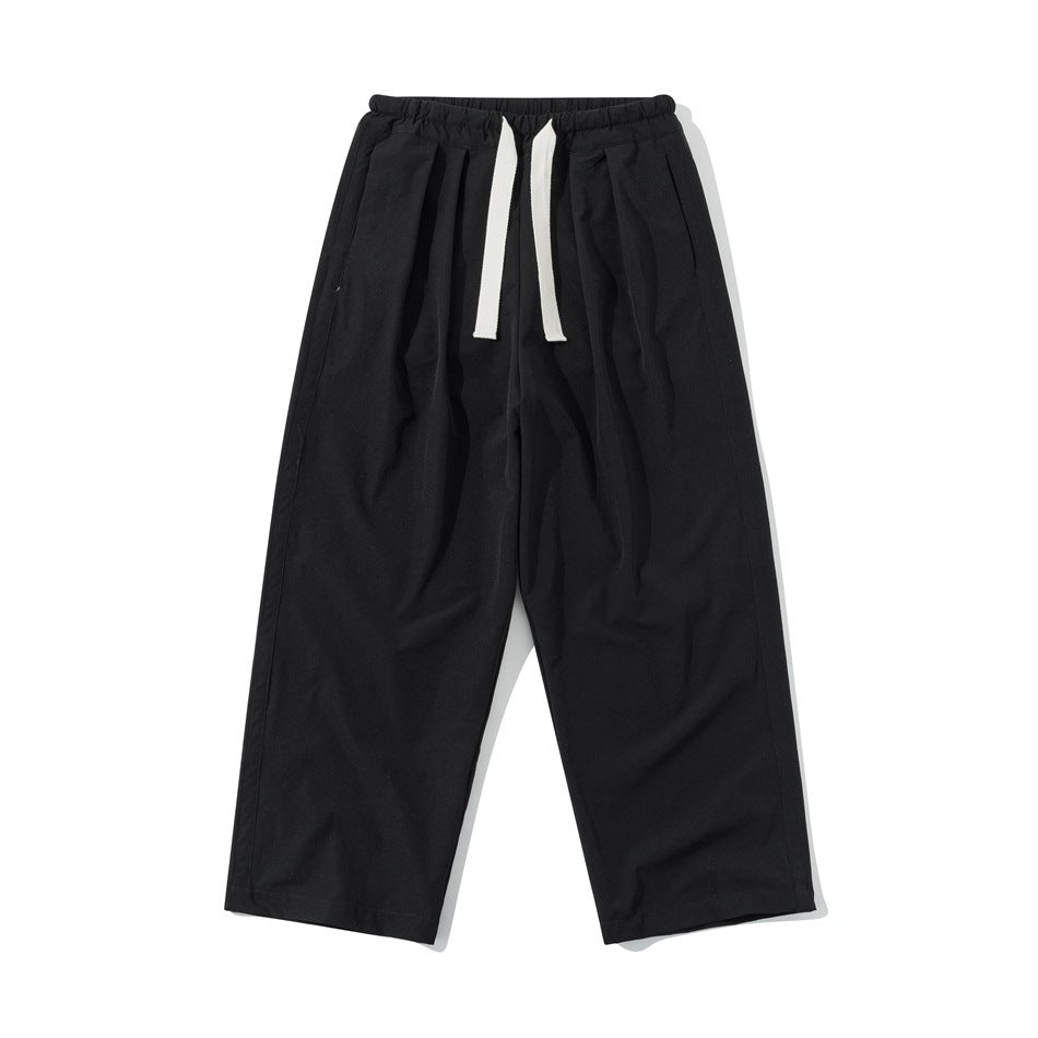 Black wide-leg drawstring pants with elastic waistband and front pleats, flat front view