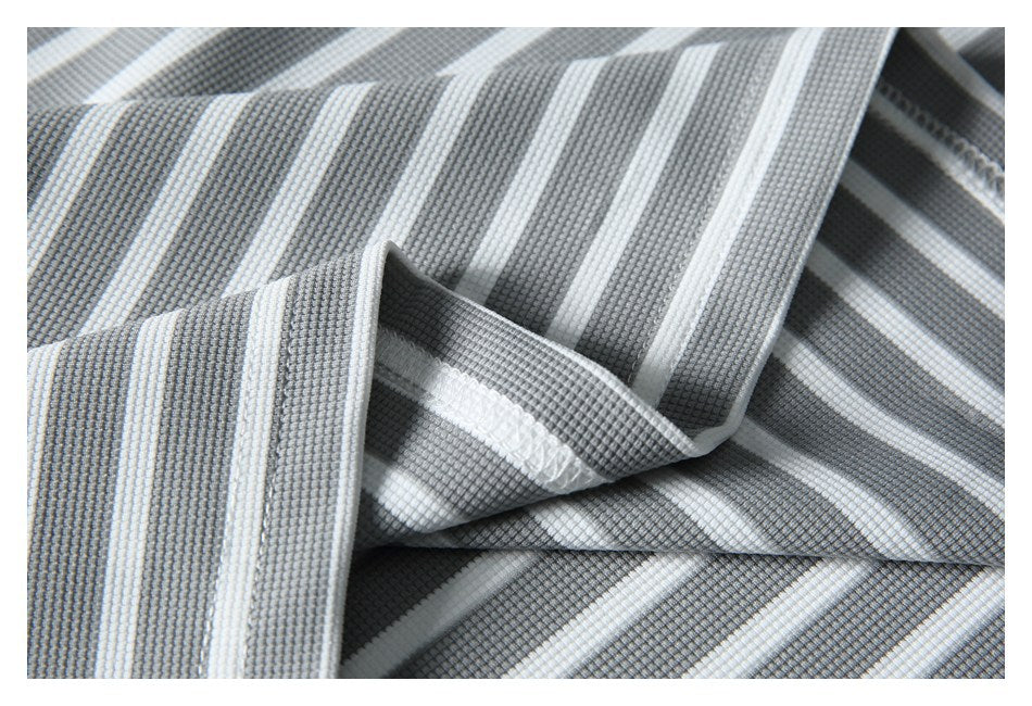 Close-up of folded gray-and-white striped fabric showing a finished seam and textured surface.