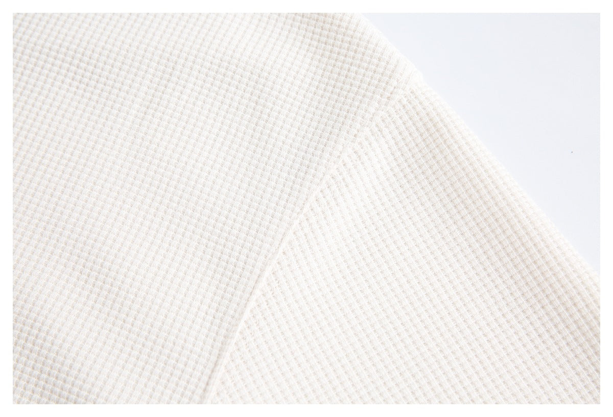 Close-up showing the off-white garment's fine waffle-knit texture and curved seam.