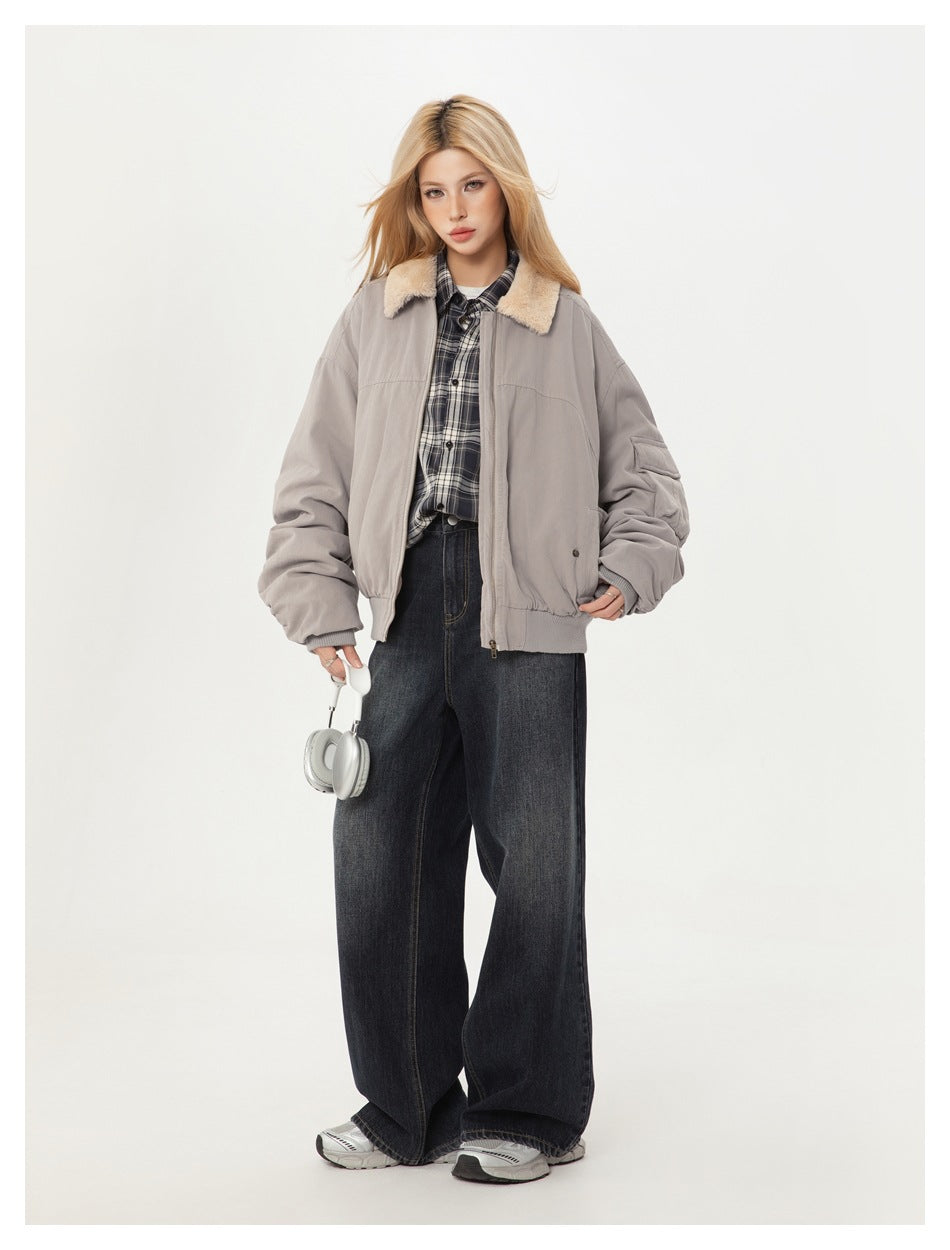 Model wearing light gray bomber jacket with beige plush collar over a plaid shirt and wide-leg dark jeans