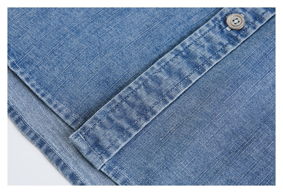 Close-up of blue denim stitching and a buttoned placket.
