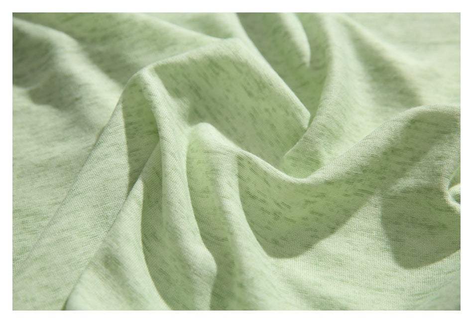 Close-up of pale sage-green fabric draped into soft folds, showing its subtle woven texture.