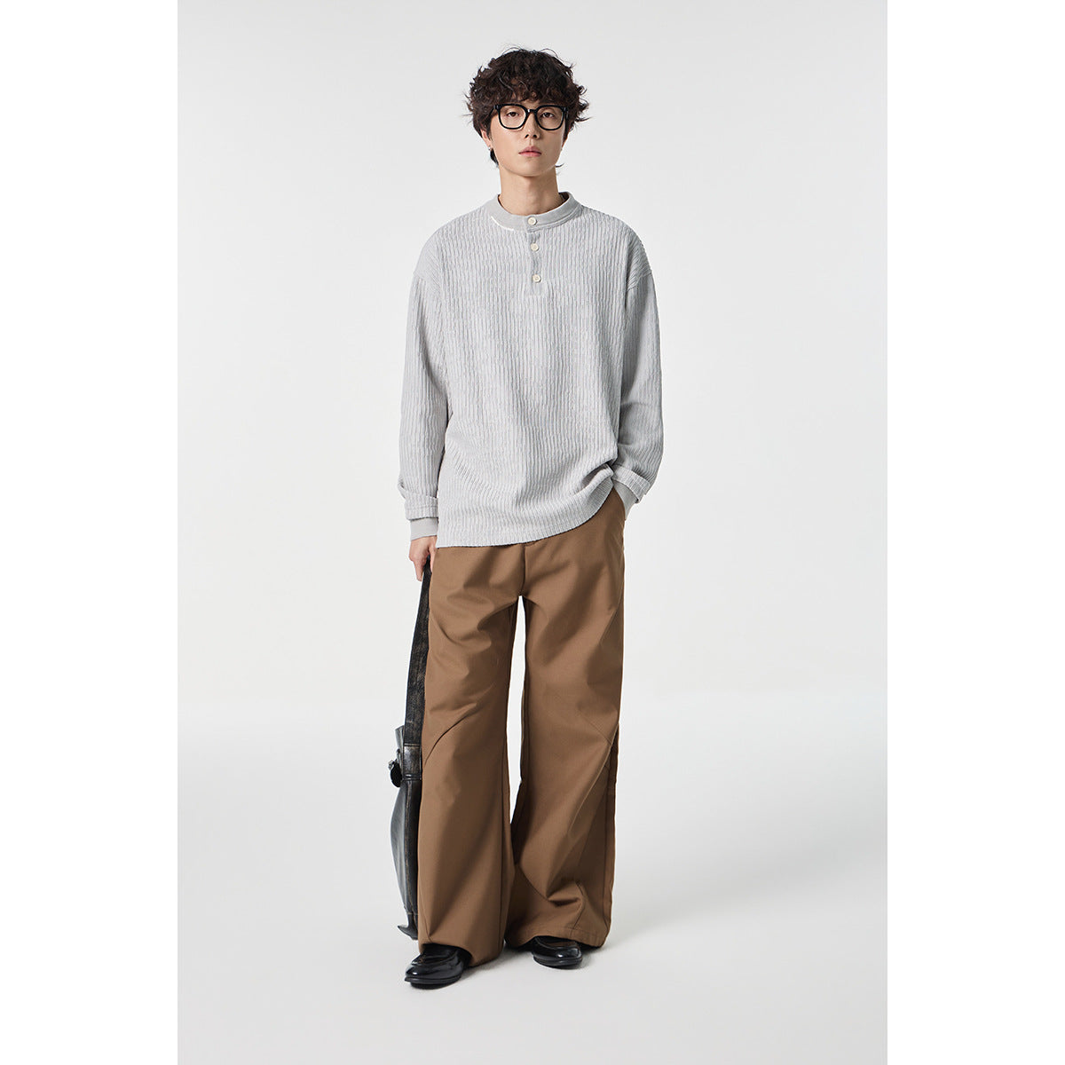 Model wearing a light gray ribbed long-sleeve Henley with brown wide-leg trousers.