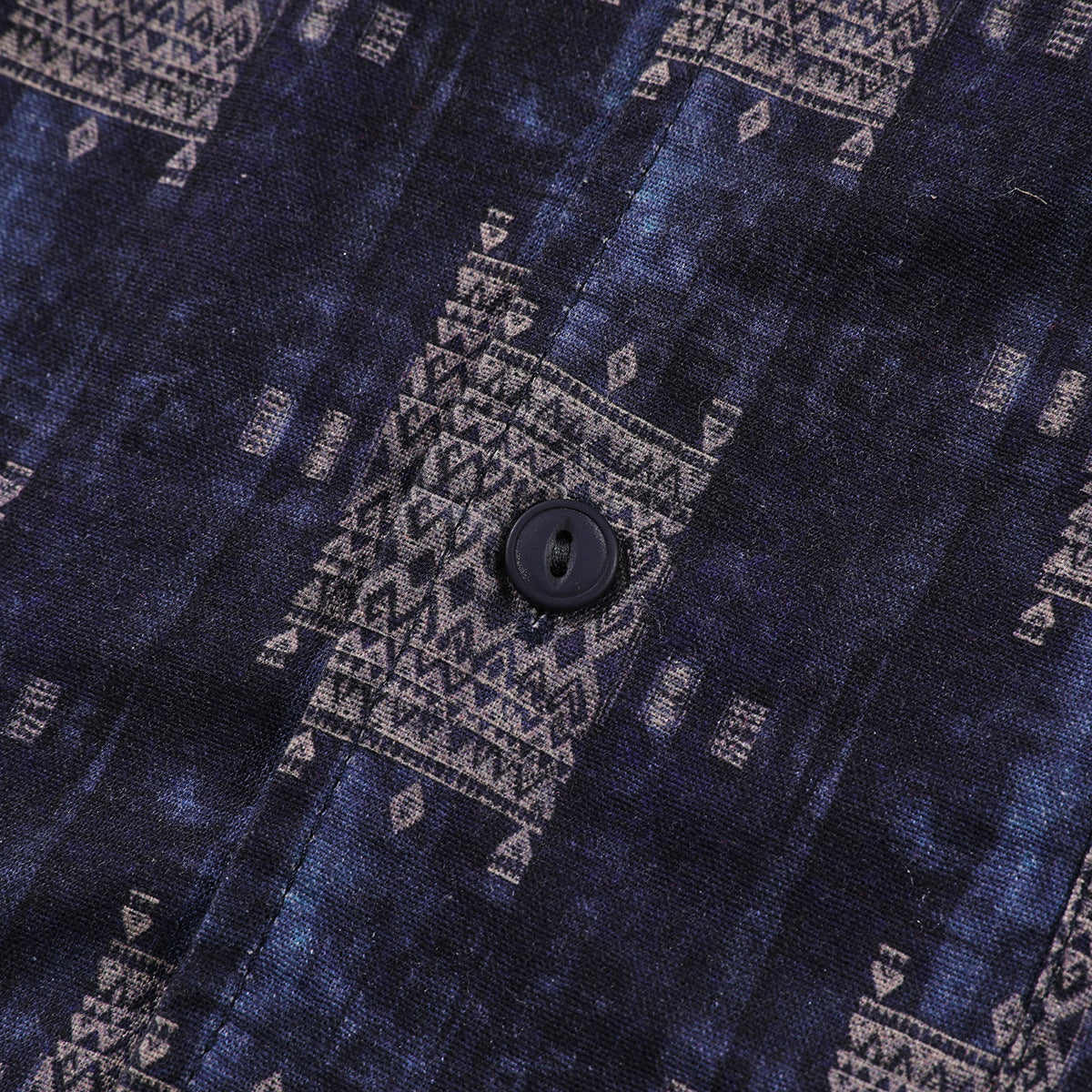 Close-up of a dark navy shirt with muted geometric motifs and a black button.