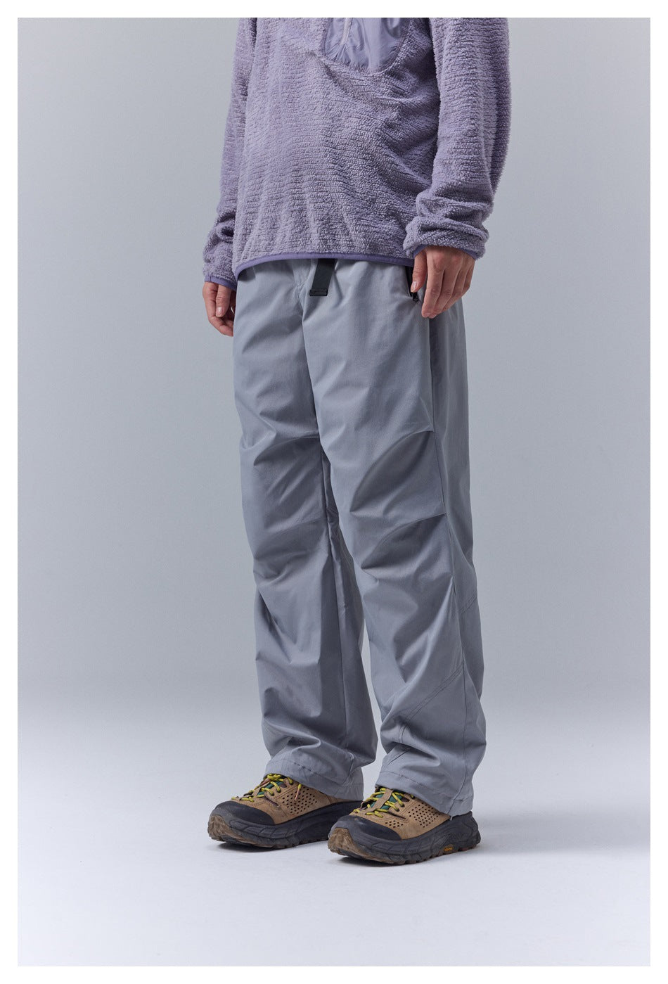 Model wearing gray wide-leg pants with a purple textured pullover and tan hiking shoes, front three-quarter view