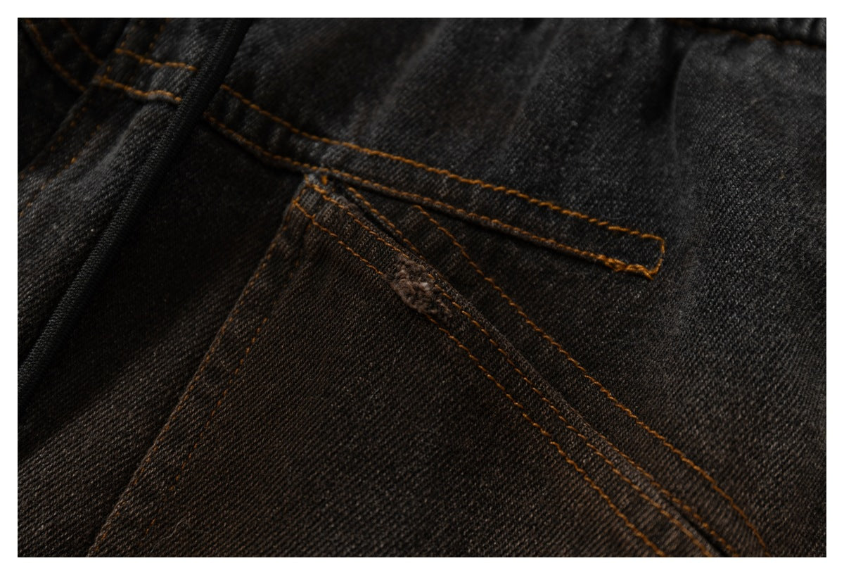 Close-up of a charcoal denim pocket edge and reinforced seams with ochre stitching.