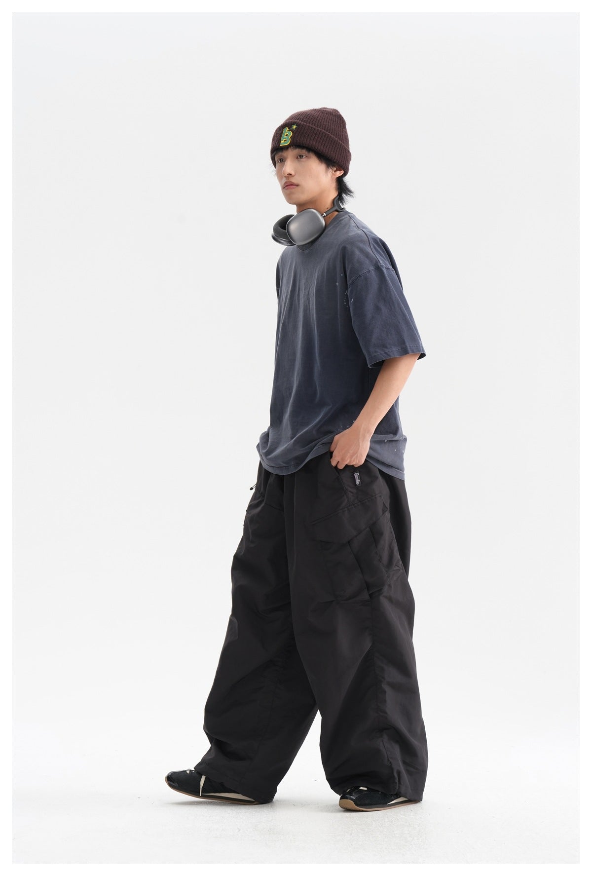 Model wearing oversized black cargo pants with a navy T-shirt and a burgundy knit beanie.
