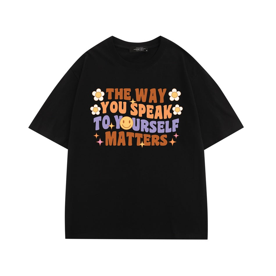 Black short-sleeve T-shirt with colorful retro slogan print, daisies and smiley face on the chest