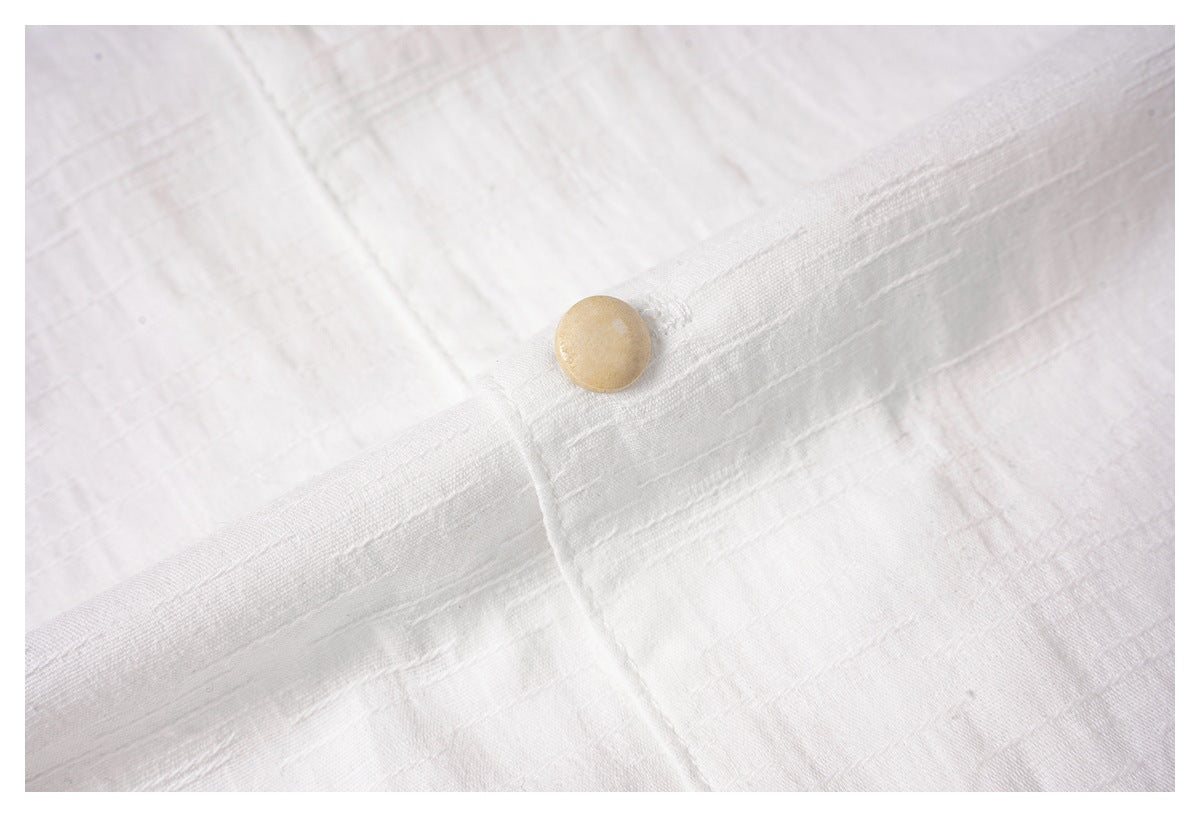 Close-up of a tan button on the white shirt's textured front placket.