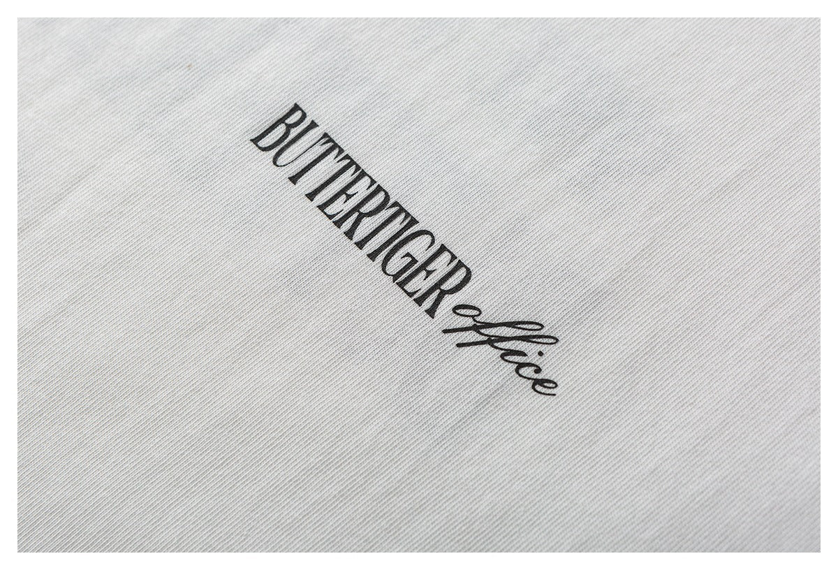 Close-up of a small black “BUTTERTIGER office” print on white fabric.