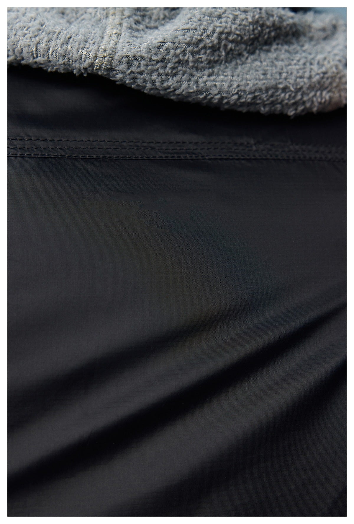 Close-up showing fuzzy blue-gray outer fabric and a smooth dark lining with stitching.
