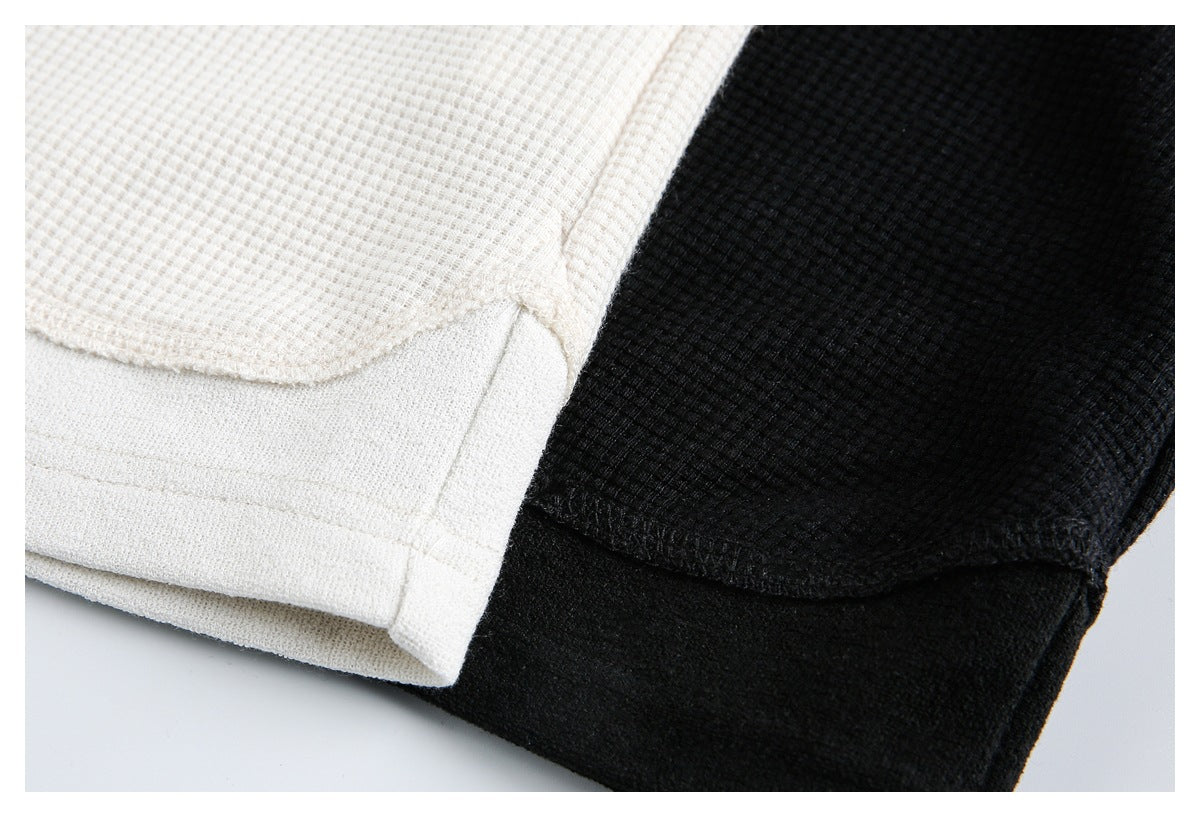 Close-up of cream and black waffle-textured garment hems with stitched edges.