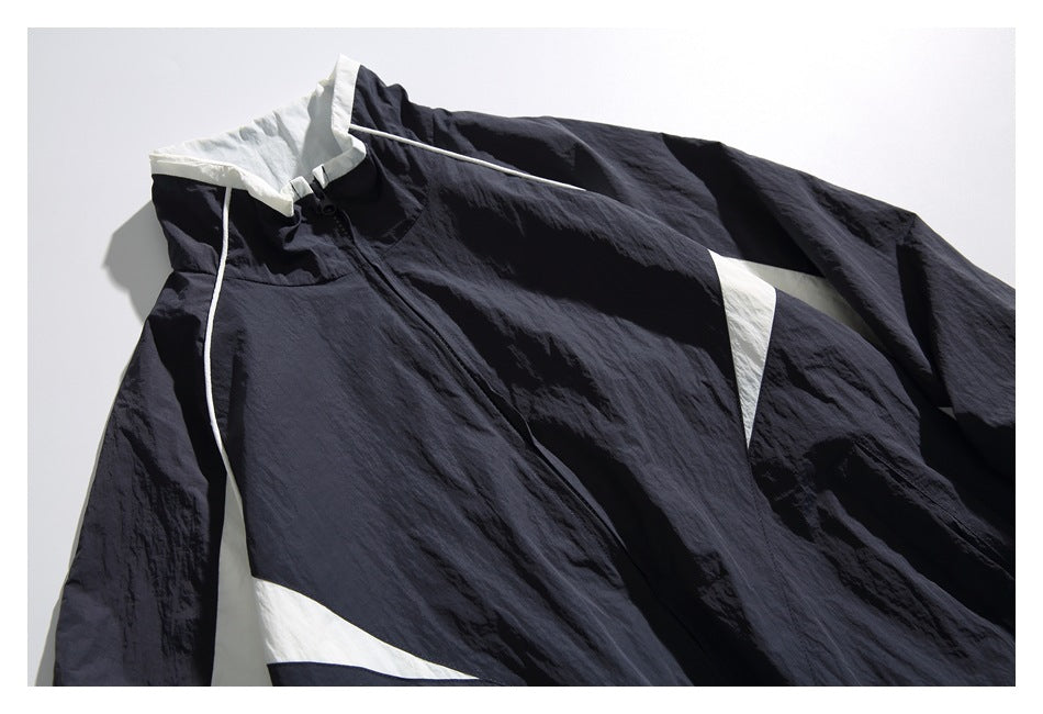 Close-up of the navy windbreaker’s front zipper, raised collar, white piping, and contrasting panels.