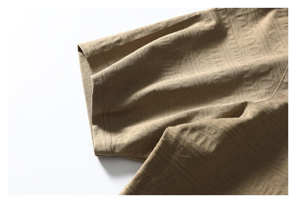 Close-up of the tan shirt's sleeve hem and raised geometric fabric pattern.