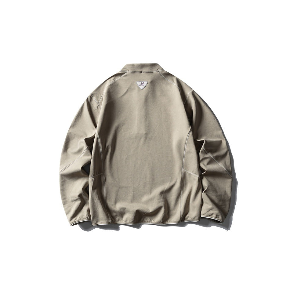 Back view of a taupe-gray long-sleeved top with a high collar, curved panel seams, and a small upper-back patch.