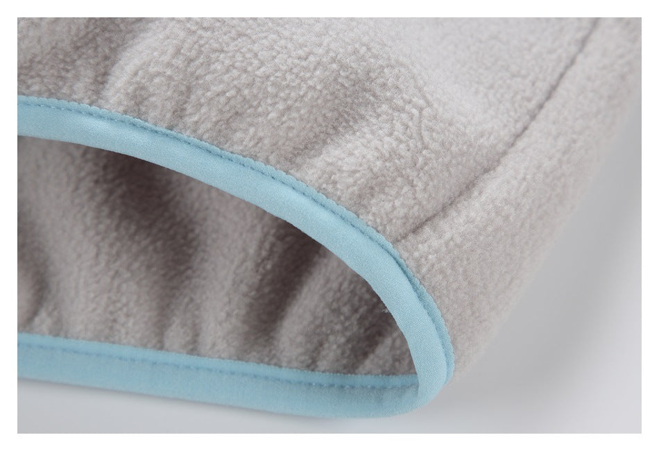 Curved edge of pale gray fuzzy fabric finished with light blue binding.