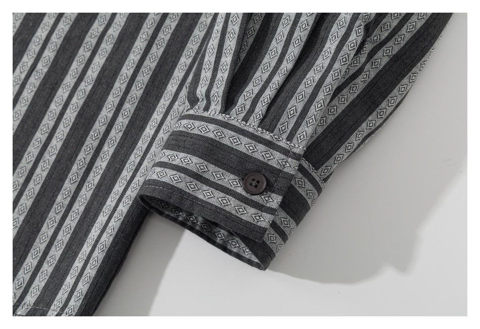 Close-up of a buttoned cuff on the gray shirt with alternating dark and diamond-patterned stripes.