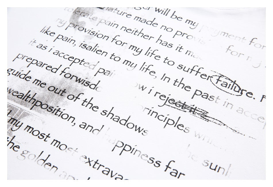 Angled close-up of black English text printed across white garment fabric, with portions of the lettering cropped.
