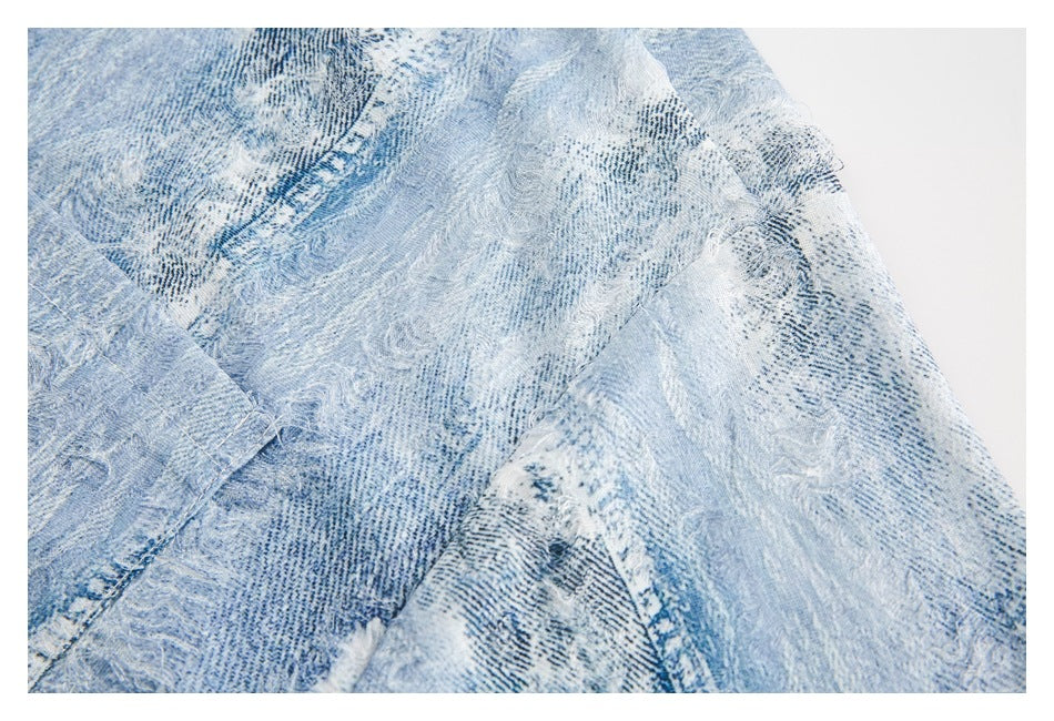 Close-up of the light blue distressed denim shirt's patterned fabric and seam.