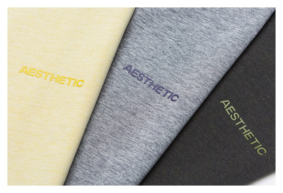 Close-up of cream, heather gray, and charcoal fabric colorways, each printed with “AESTHETIC.”