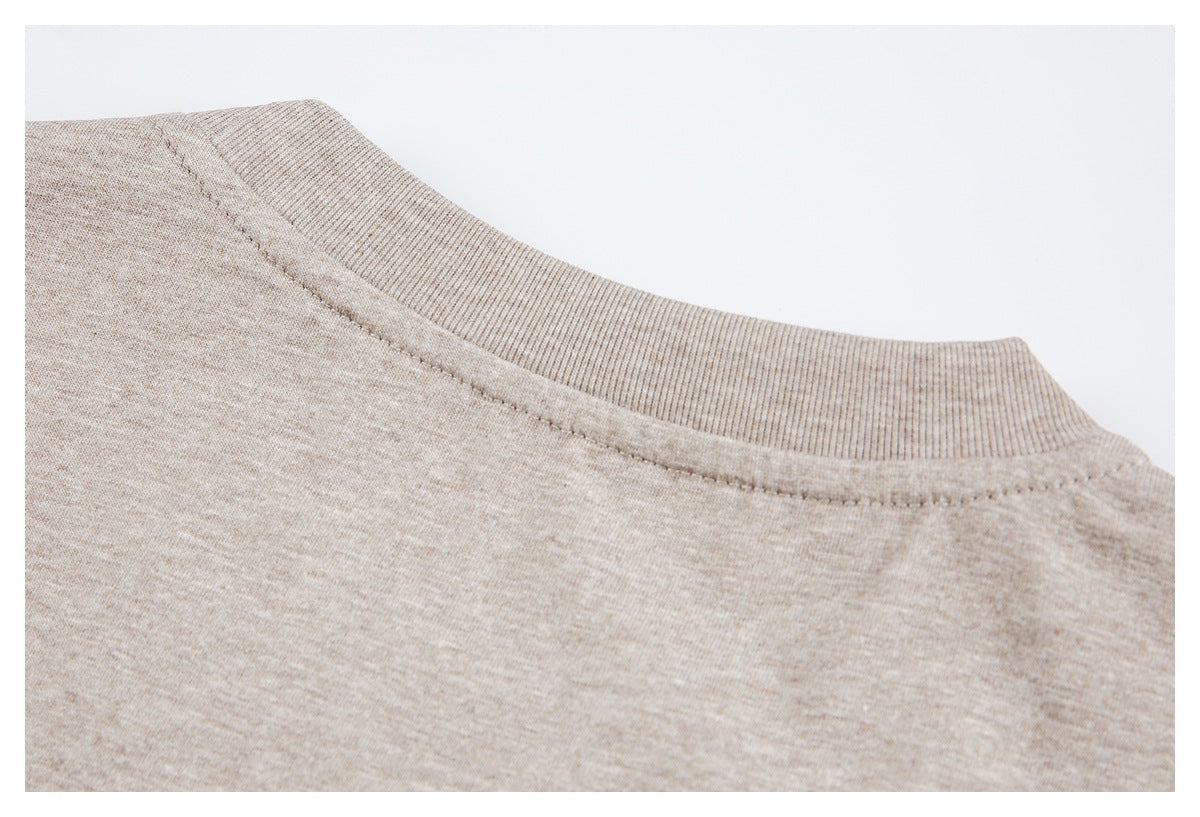 Close-up of a beige heather knit garment's ribbed crew neckline and stitched collar seam.