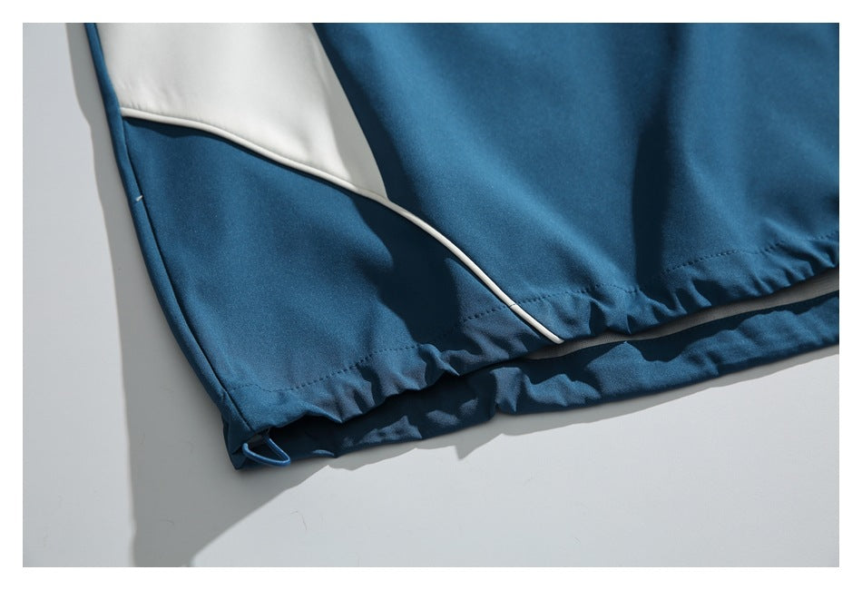 Close-up of a teal garment's gathered hem, light curved side panel, and small drawcord loop.