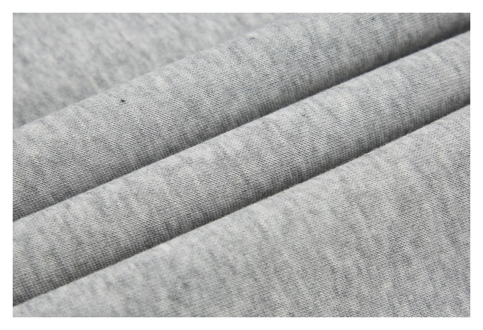 Macro view of light gray knit fabric folded into soft diagonal ridges.