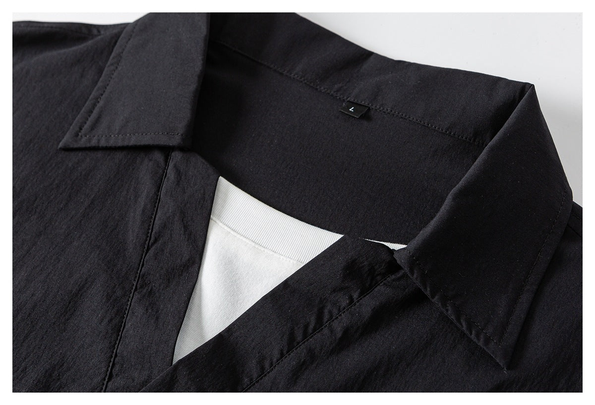 Close-up of black shirt collar and V-neck opening with white layered inner piece and size label