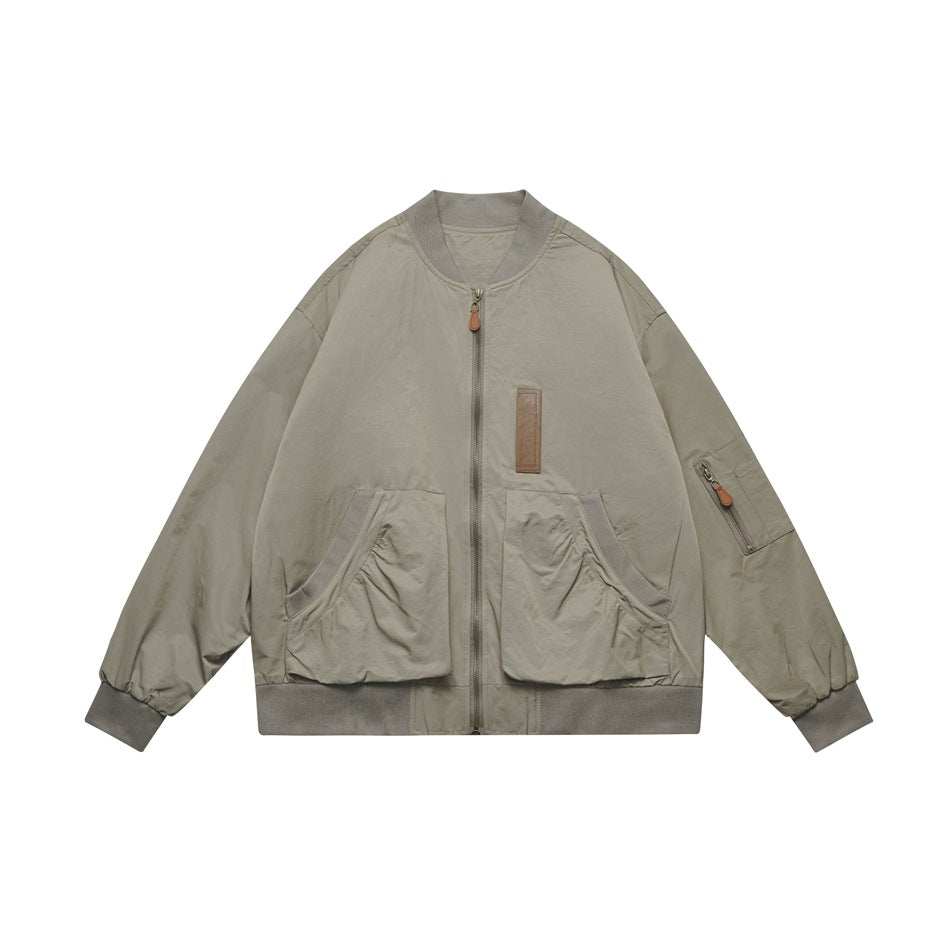 Gray-green bomber-style zip jacket with ribbed collar, ruched patch pockets, sleeve zip pocket and brown chest tab, flat lay
