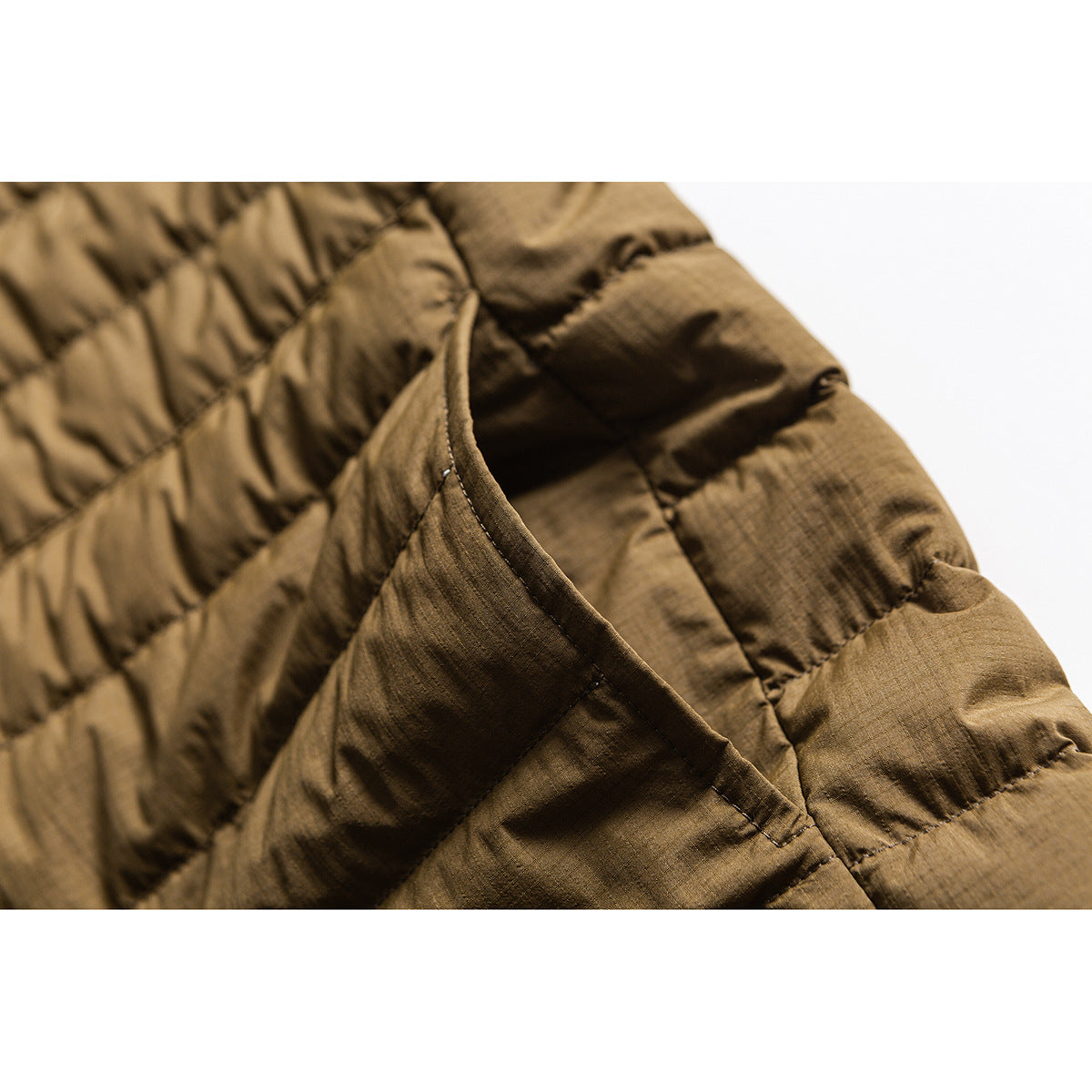 Close-up of a brown quilted jacket's curved pocket opening and horizontal padded stitching.
